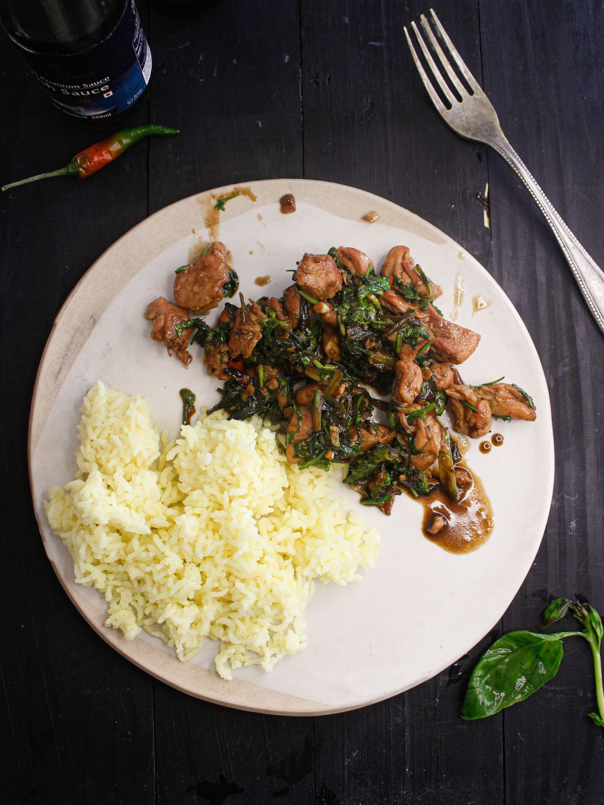 белая тарелка с рисом и тайской базиликовой курицей на черном столе