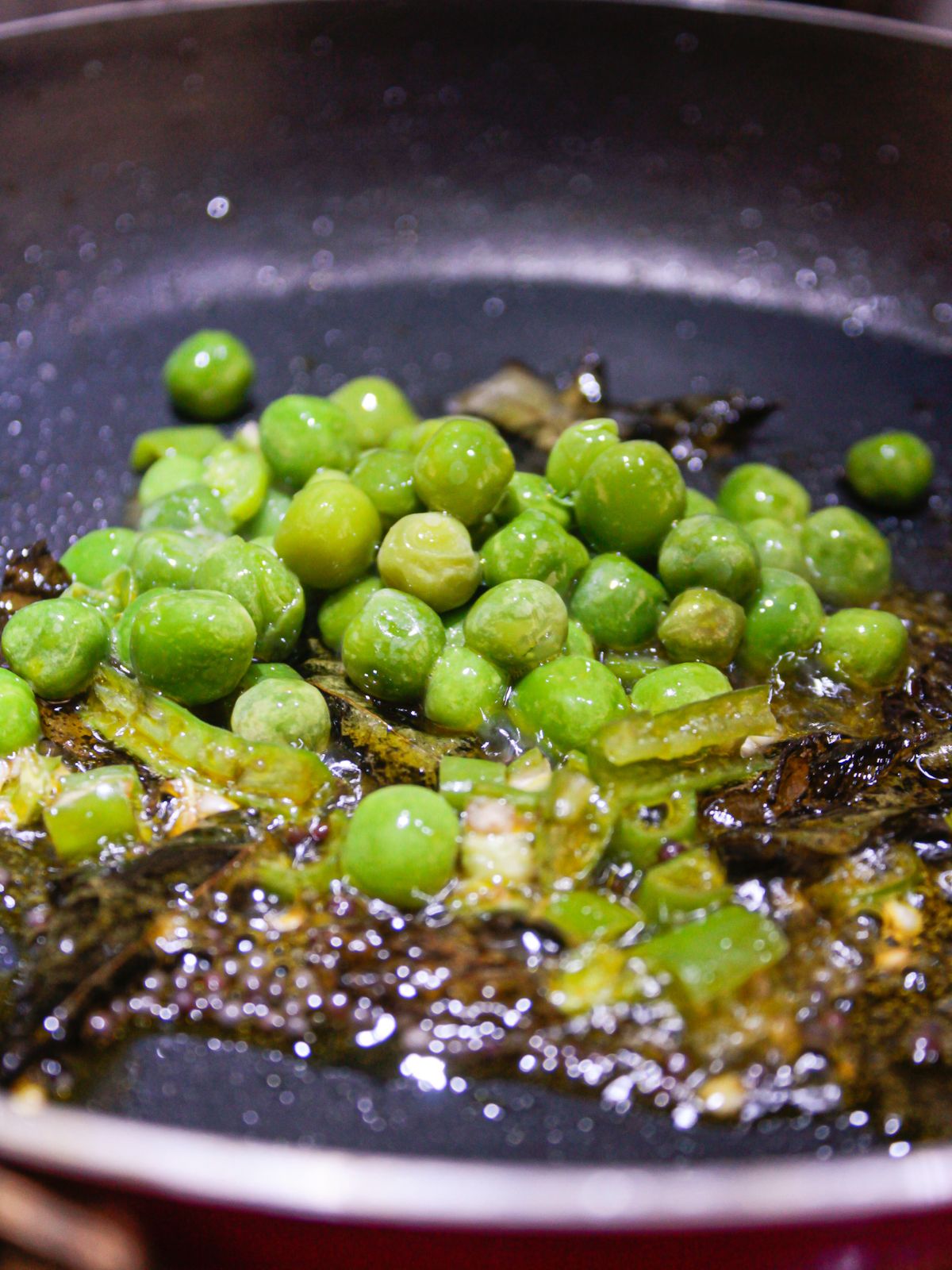 Горошек и зеленый чили в масле в сковороде