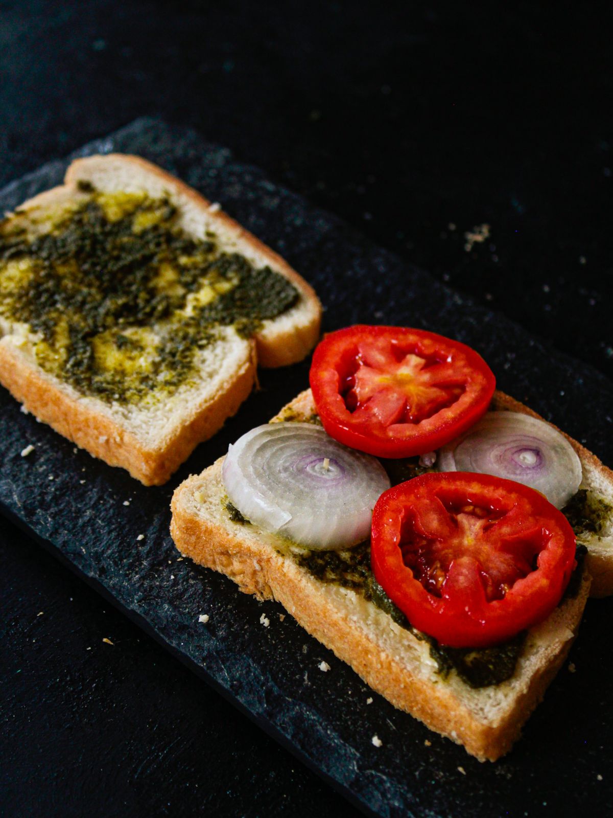 два ломтика хлеба с зеленым чатни и овощами на столе