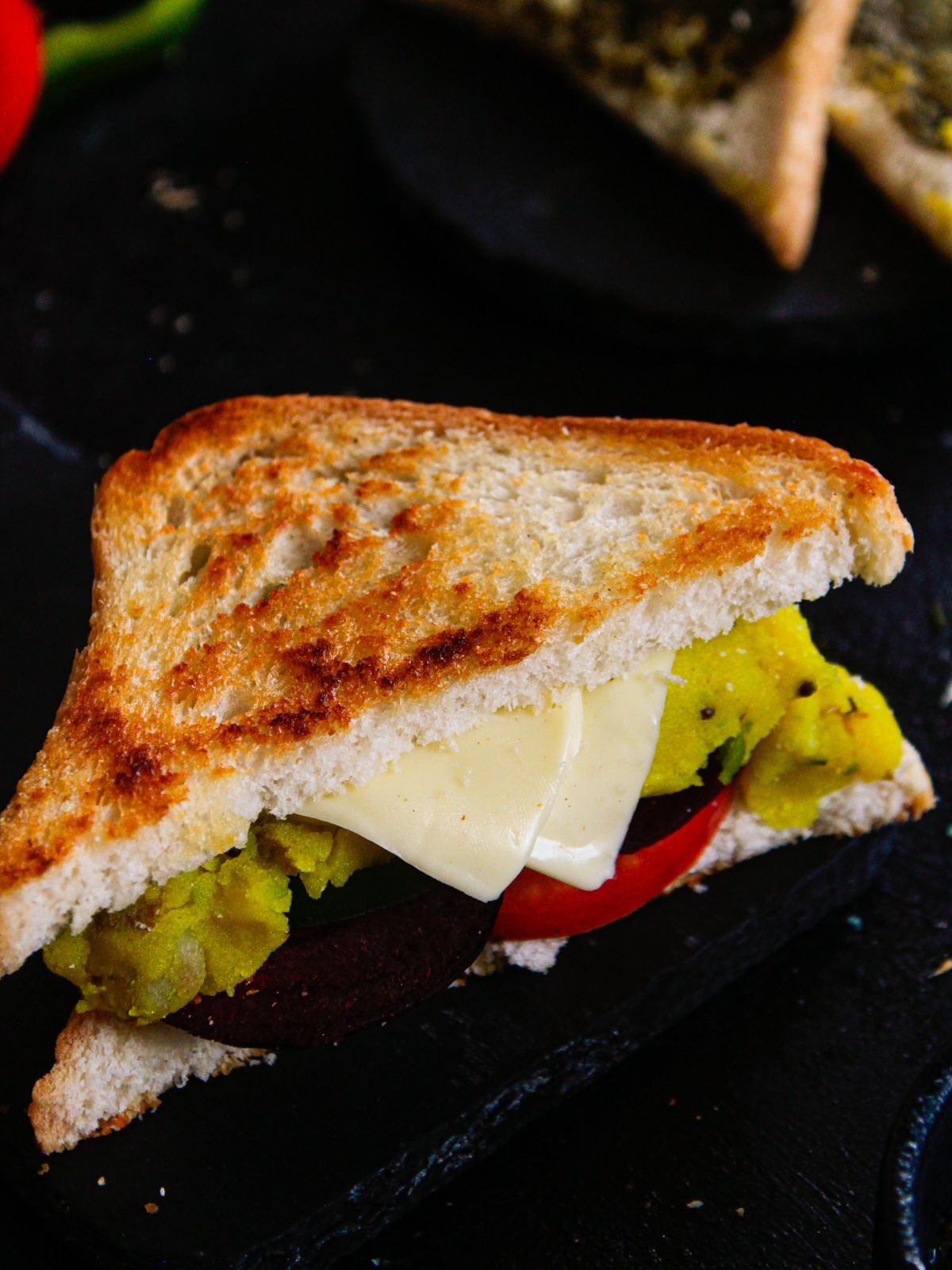 сэндвич с сыром и овощами на черном столе