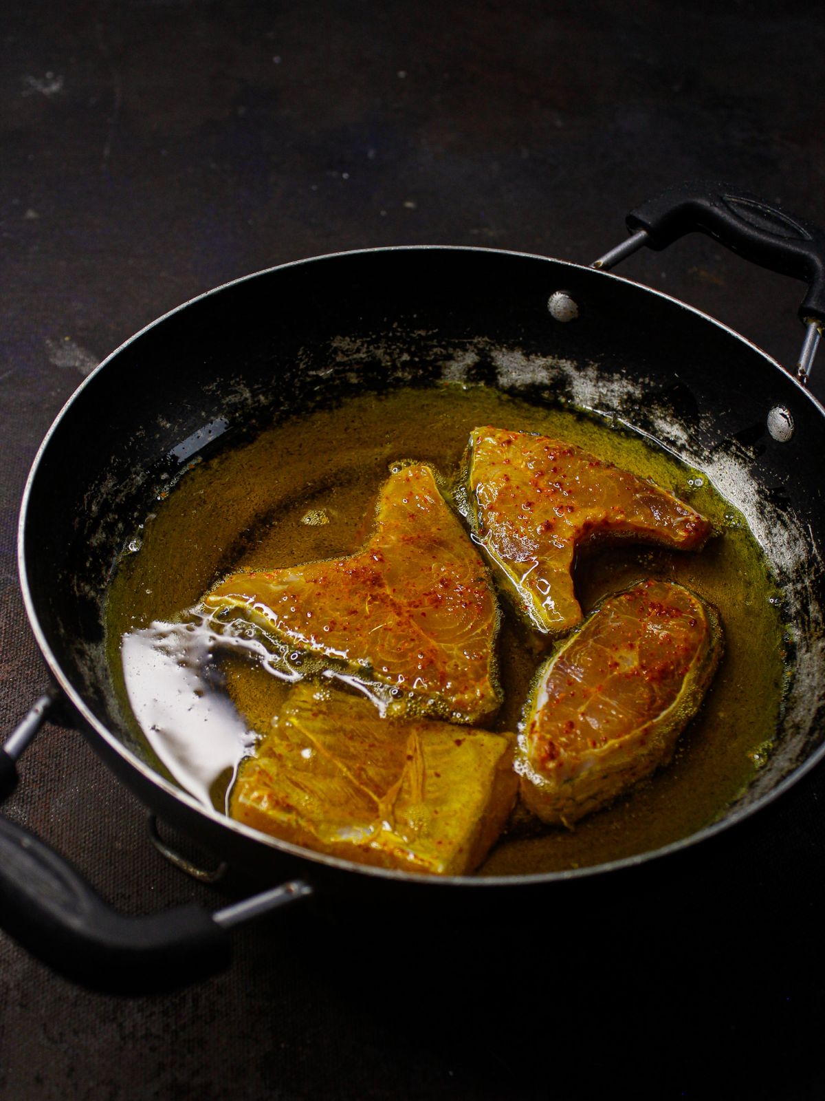 четыре куска рыбы в горячем масле в сковороде